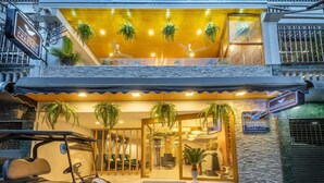 A hotel entrance with a covered outdoor seating area, a reception desk, and a golf cart parked outside. - Tori Prestige Bangkok Hotel (Bangkok)