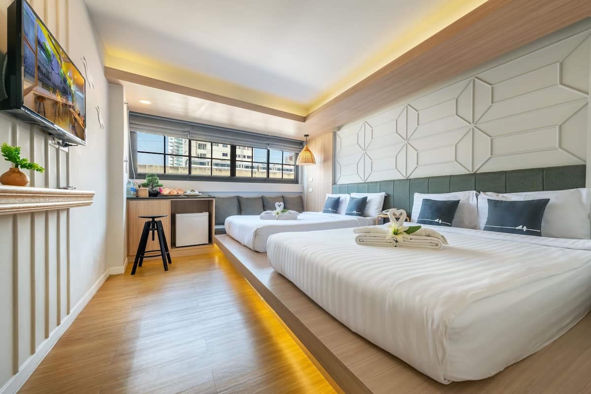Une chambre d’hôtel avec deux lits, un bureau, une télévision et une fenêtre donnant sur la ville.
