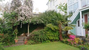 Un jardín con diversas plantas, una palmera y una escalera de ladrillo que conduce a un edificio.