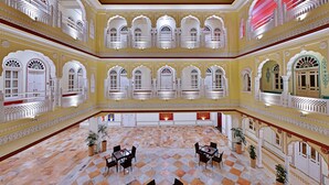 Tilava aula, jossa on ruutukuviollinen lattia, useita parvekkeita valkoisilla kaiteilla ja useita ruukkukasveja.