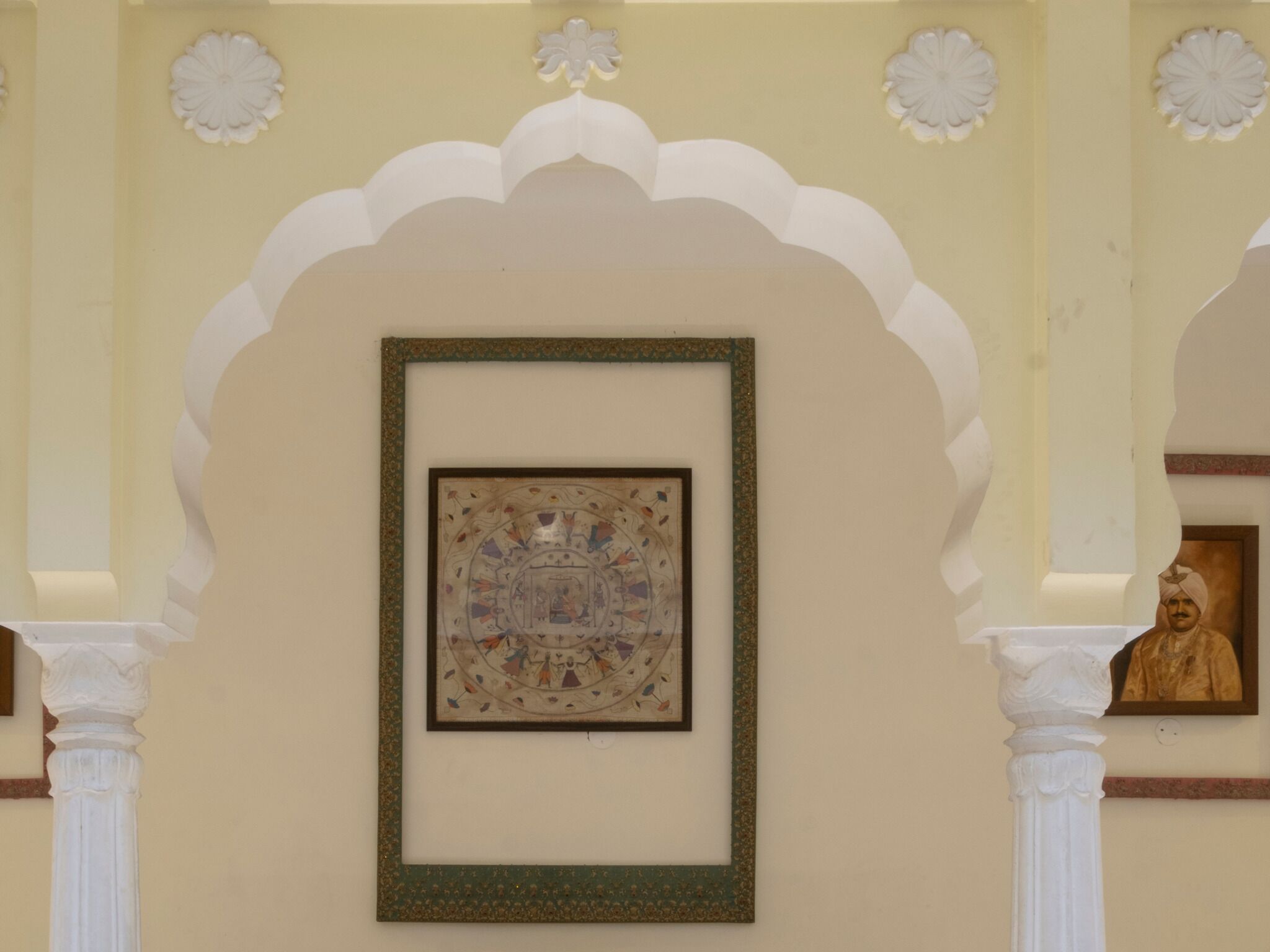 Una obra de arte en un marco colgada en una pared, con un arco decorativo y una estatua.