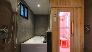 Un baño moderno con una bañera grande, una ducha y una puerta de madera que da a un espacio pequeño con un banco.
