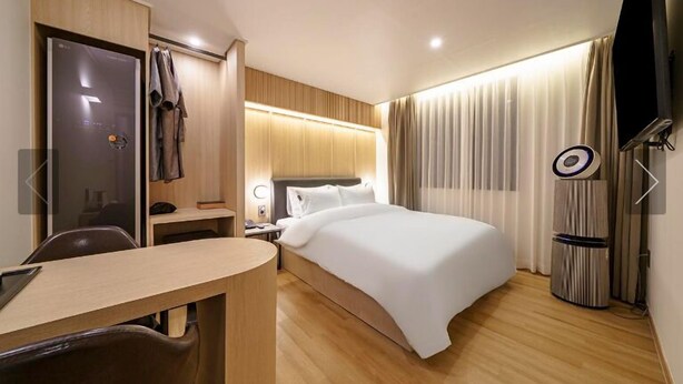Una habitación de hotel con cama, escritorio, silla, armario y televisor.