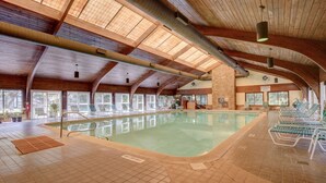 An indoor swimming pool with a wooden ceiling, tiled floor, and sunlit windows. - Ocean Dunes 104 – Spacious oceanfront condo at Ocean Dunes in Kure Beach (Kure Beach)