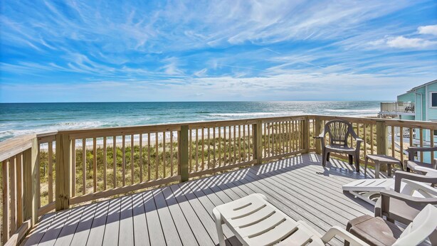 A wooden deck with chairs overlooking the ocean. - Ocean Dunes 104 – Spacious oceanfront condo at Ocean Dunes in Kure Beach (Kure Beach)