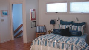 Ein Schlafzimmer mit einem Bett, einem Sessel, einer Lampe und einem Fenster.