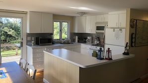 Eine moderne Küche mit weißen Schränken, einer zentralen Kochinsel und einem Essbereich mit Holztisch und -stühlen.
