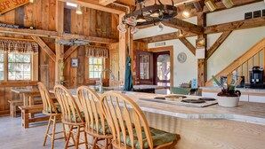A rustic interior with wooden beams, a central island with seating, and a kitchen area. - Mountain Lodge Retreat (Newry)