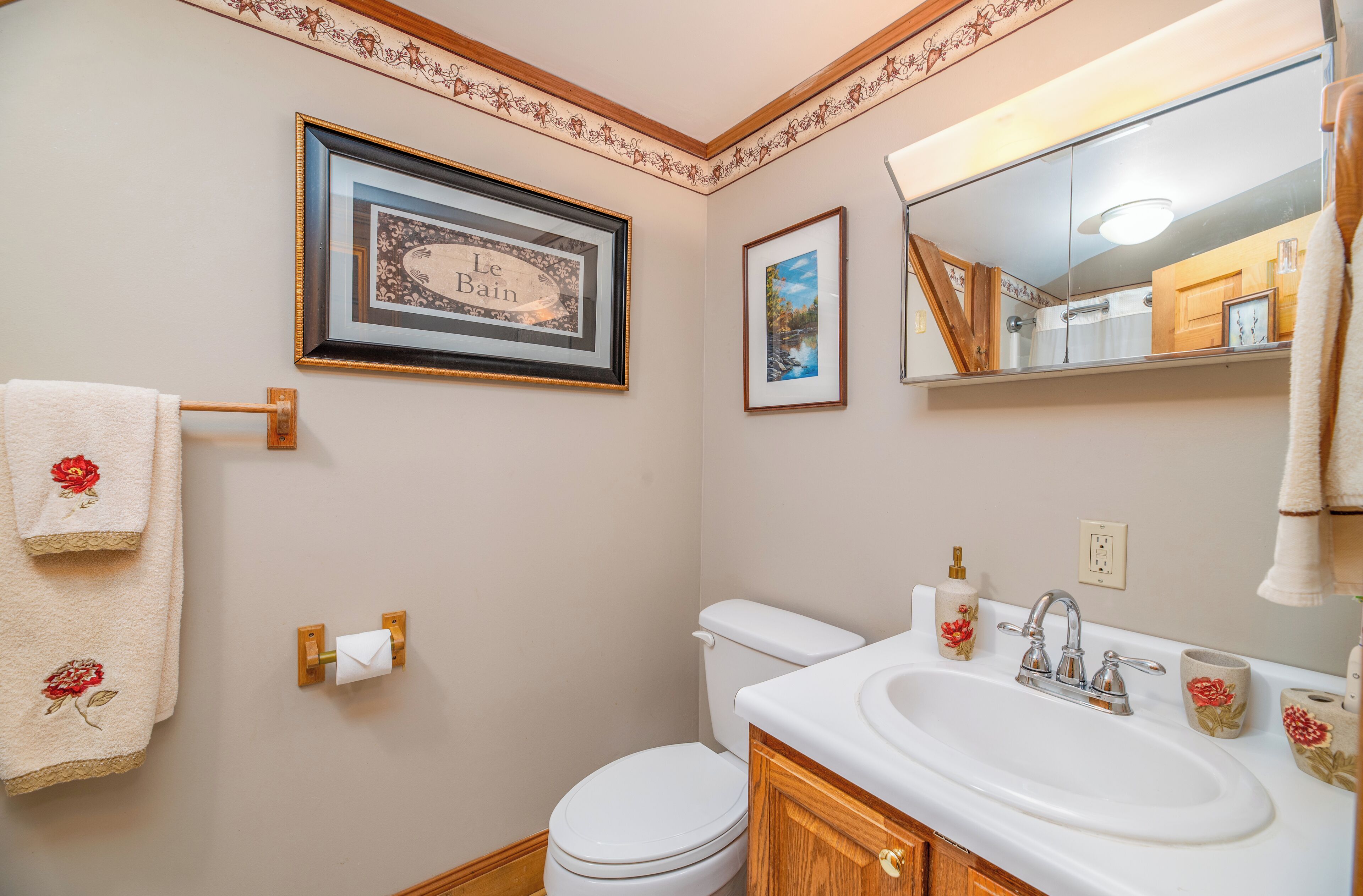 A bathroom with a toilet, sink, and framed pictures on the wall.