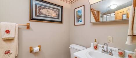 A bathroom with a toilet, sink, and framed pictures on the wall.