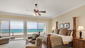 A bedroom with a bed, a nightstand, a chair, a dresser, and a ceiling fan. There is a large window with a view of the ocean. - Tuscany Sunrise - A Luxury Retreat for Discerning Guests (Navarre)