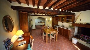 A rustic kitchen with exposed wooden beams, a dining table with chairs, a fireplace, and a tiled floor. - Rustic renovated, with every modern comfort, private pool and garden (Domazzano)