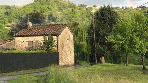 A stone building with a tiled roof, surrounded by greenery and a hill in the background. - Rustic renovated, with every modern comfort, private pool and garden (Domazzano)