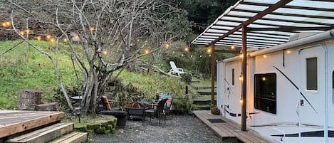 A covered outdoor area with a seating arrangement and a white RV.