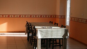 A dining area with a long table, chairs, and a patterned border on the walls. - accommodation for up to 12 people (Ferrières-Saint-Mary)