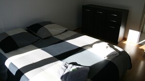 A bed with a checkered bedspread, a pillow, and a folded towel. There is a dark-colored wardrobe against the wall. - accommodation for up to 12 people (Ferrières-Saint-Mary)