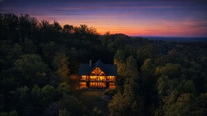 A house surrounded by dense forest with a visible balcony and a chimney. - A View To Remember: MTN VIEWS! Luxury, Hot Tub, Wifi, Fireplace, Games and more (Sevierville)