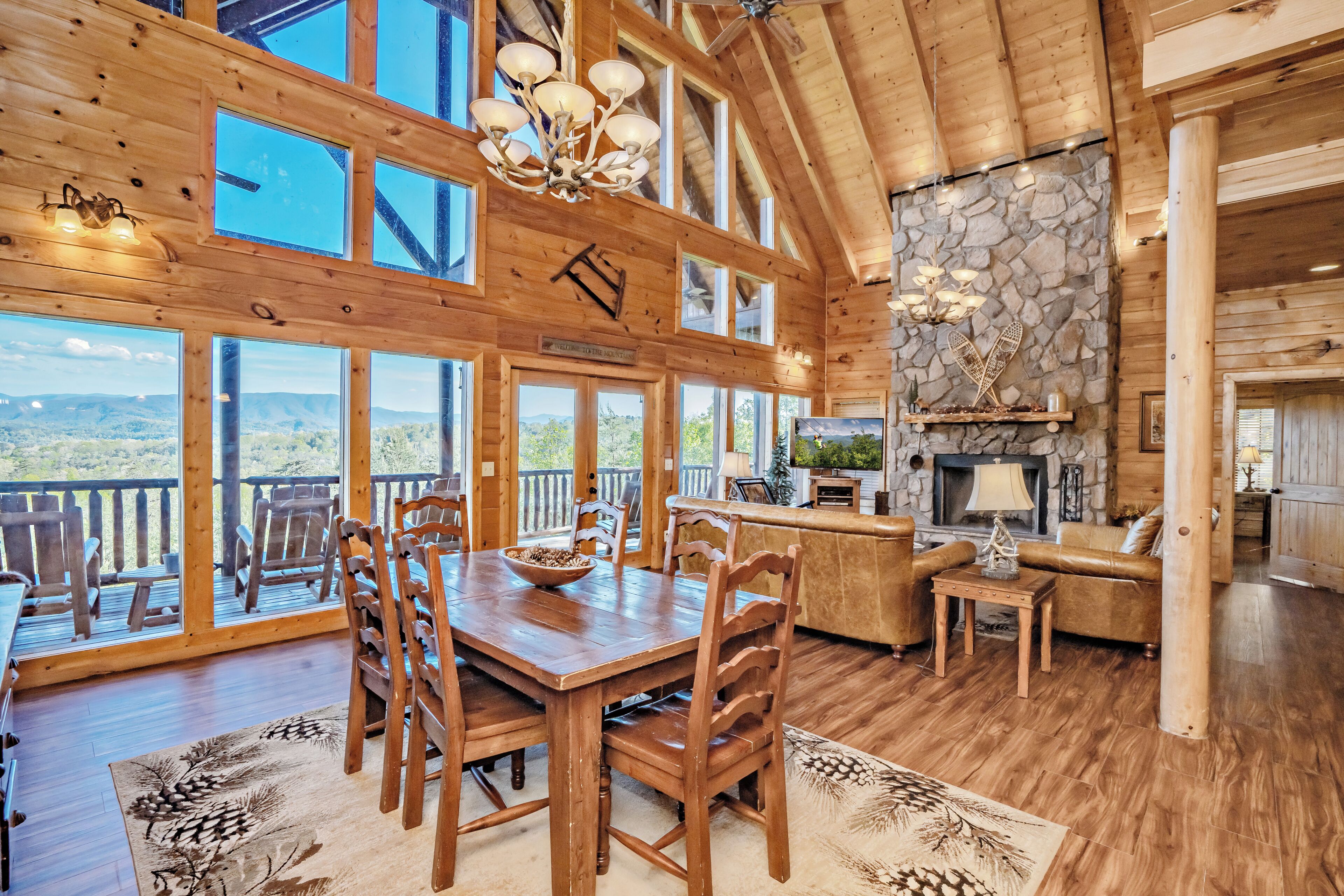 A spacious wooden interior with a dining area, kitchen, and large windows offering scenic views.