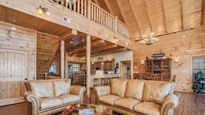 A spacious log cabin interior with leather sofas, a glass coffee table, and a dining area. - A View To Remember: MTN VIEWS! Luxury, Hot Tub, Wifi, Fireplace, Games and more (Sevierville)