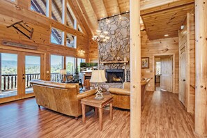 A wooden interior with a fireplace, leather sofas, and a stone wall.