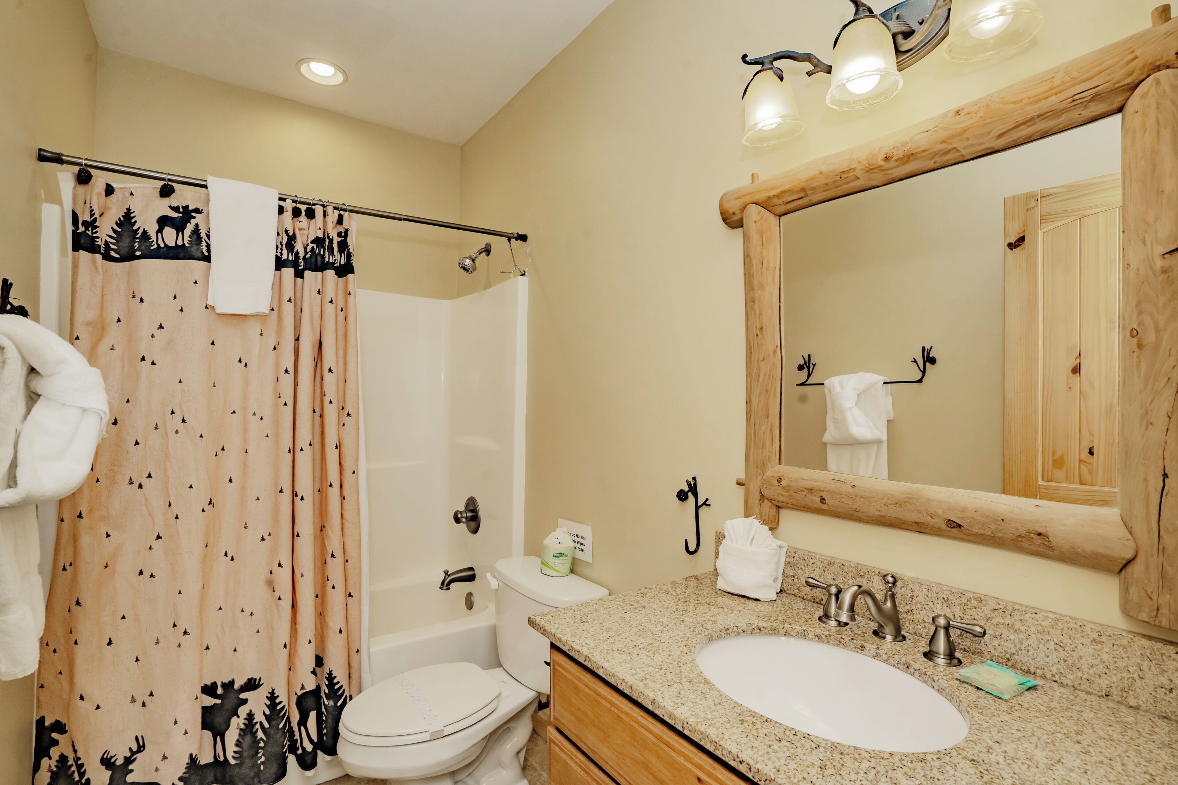 A bathroom with a shower curtain, toilet, sink, and a large mirror.