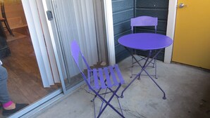 Un petit espace patio avec une chaise pliante violette et une table.