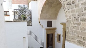 A courtyard with a staircase, outdoor seating area, and a stone wall.