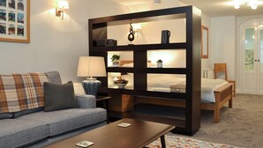 Een gezellige woonkamer met een bank, een salontafel, een boekenkast en een bed.