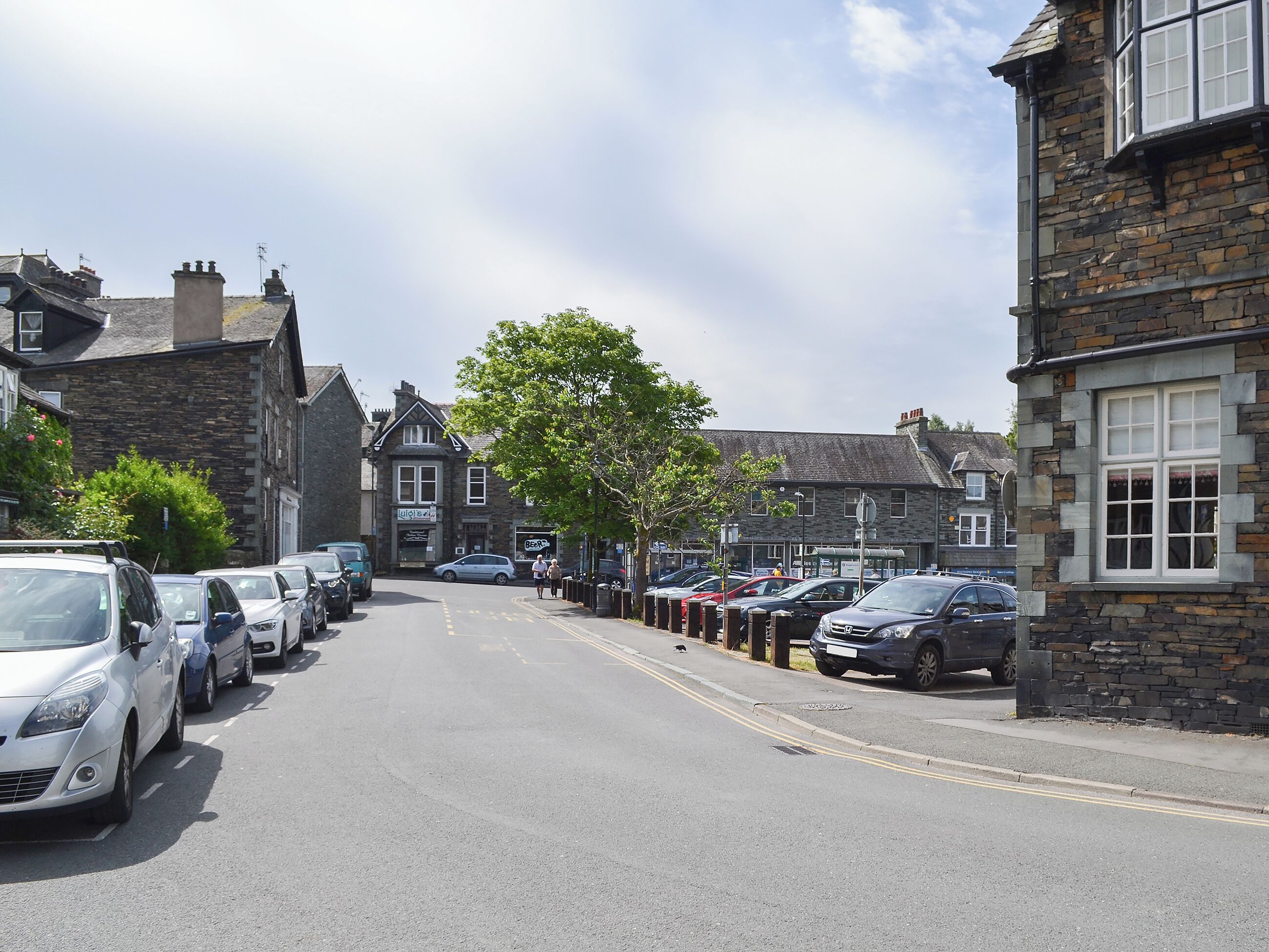 A street lined with parked cars and stone buildings.