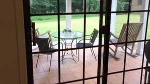 A view through a glass door to an outdoor patio with a round table and chairs, a ceiling fan, and a lawn. - Charming Summer + Fall Football Rental - Near Square & Ole Miss Camp (Oxford)