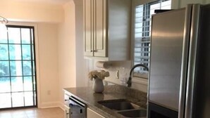 A kitchen with light-colored cabinets, a stainless steel refrigerator, and a dishwasher. - Charming Summer + Fall Football Rental - Near Square & Ole Miss Camp (Oxford)
