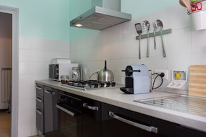 Eine Küche mit Gasherd, Toaster, Wasserkocher und verschiedenen Küchenutensilien an der Wand.