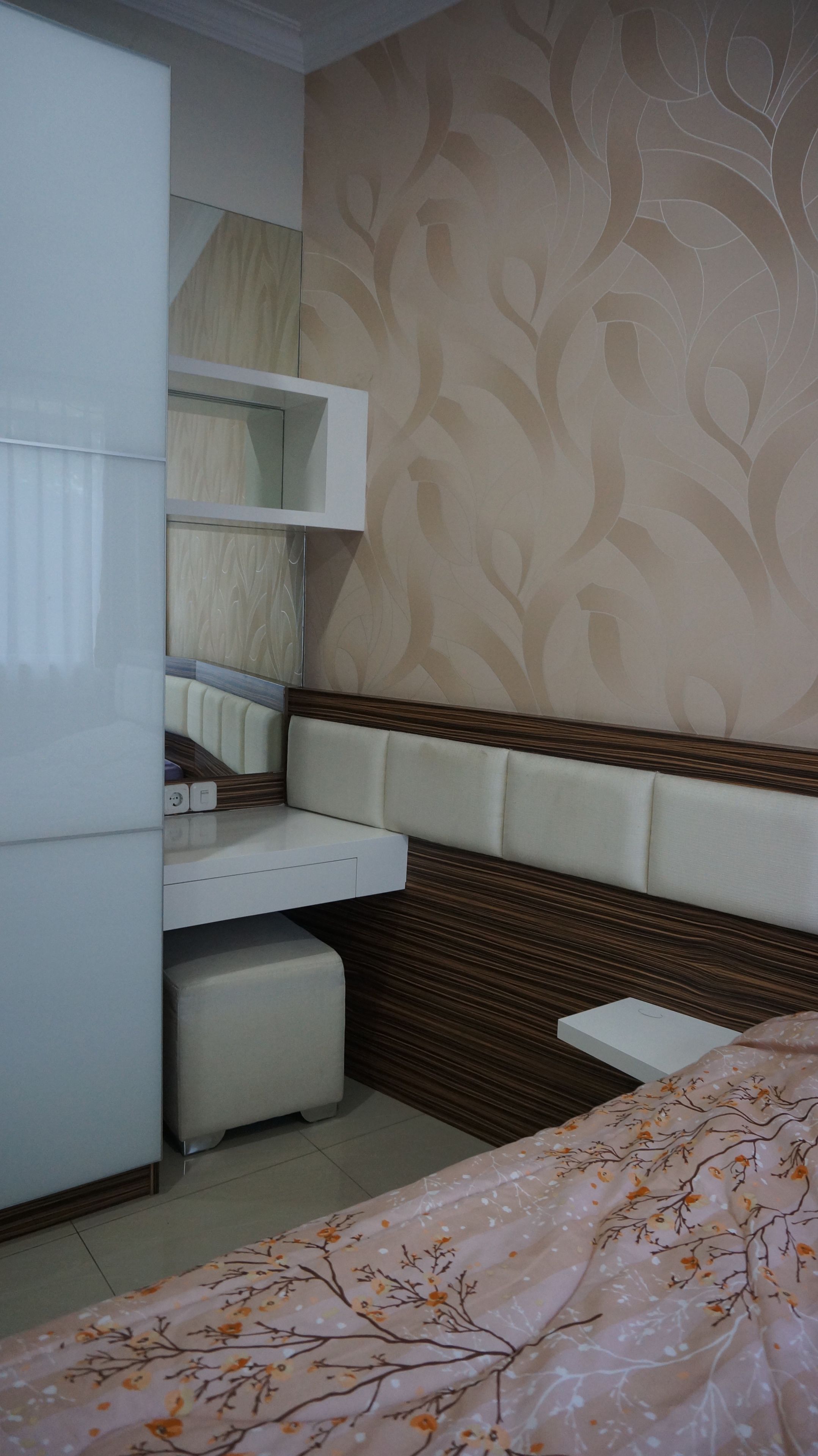 A bedroom with a bed, a wardrobe, a mirror, and a patterned wall.