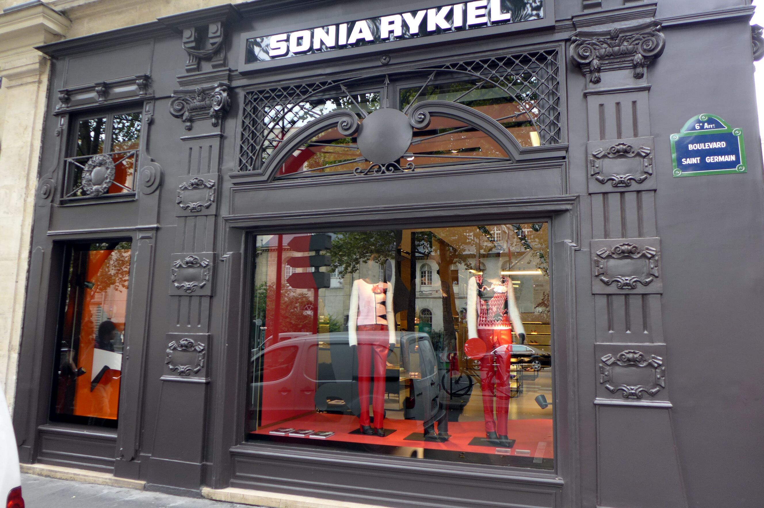 A storefront with ornate metal detailing and a large glass window displaying mannequins.