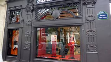 A storefront with ornate metal detailing and a large glass window displaying mannequins.