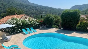 Una piscina con agua azul cristalina, rodeada de sillas de descanso y una zona de terraza.