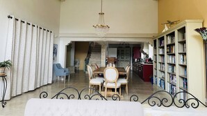Una sala de estar amplia con comedor, una escalera que sube a otro nivel y una estantería llena de libros.