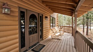 Een houten chalet met een veranda, twee deuren met decoratief glas en twee comfortabele stoelen.