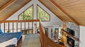 Une chambre à coucher de style loft avec une grande fenêtre, une cheminée et un plafond en bois.