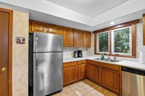 Una cocina con armarios de madera, un refrigerador de acero inoxidable, una cafetera y un lavavajillas.