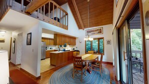 A modern kitchen with wooden cabinets, a dining area with a round table and chairs, and a staircase leading to an upper level.