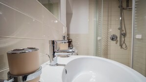 A bathroom with a white sink, chrome faucet, and a glass shower enclosure. - independent apartment in Trastevere (Roma)