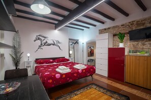Un dormitorio moderno con una cama grande, un armario de madera, un escritorio con un tazón y una planta en la cómoda.