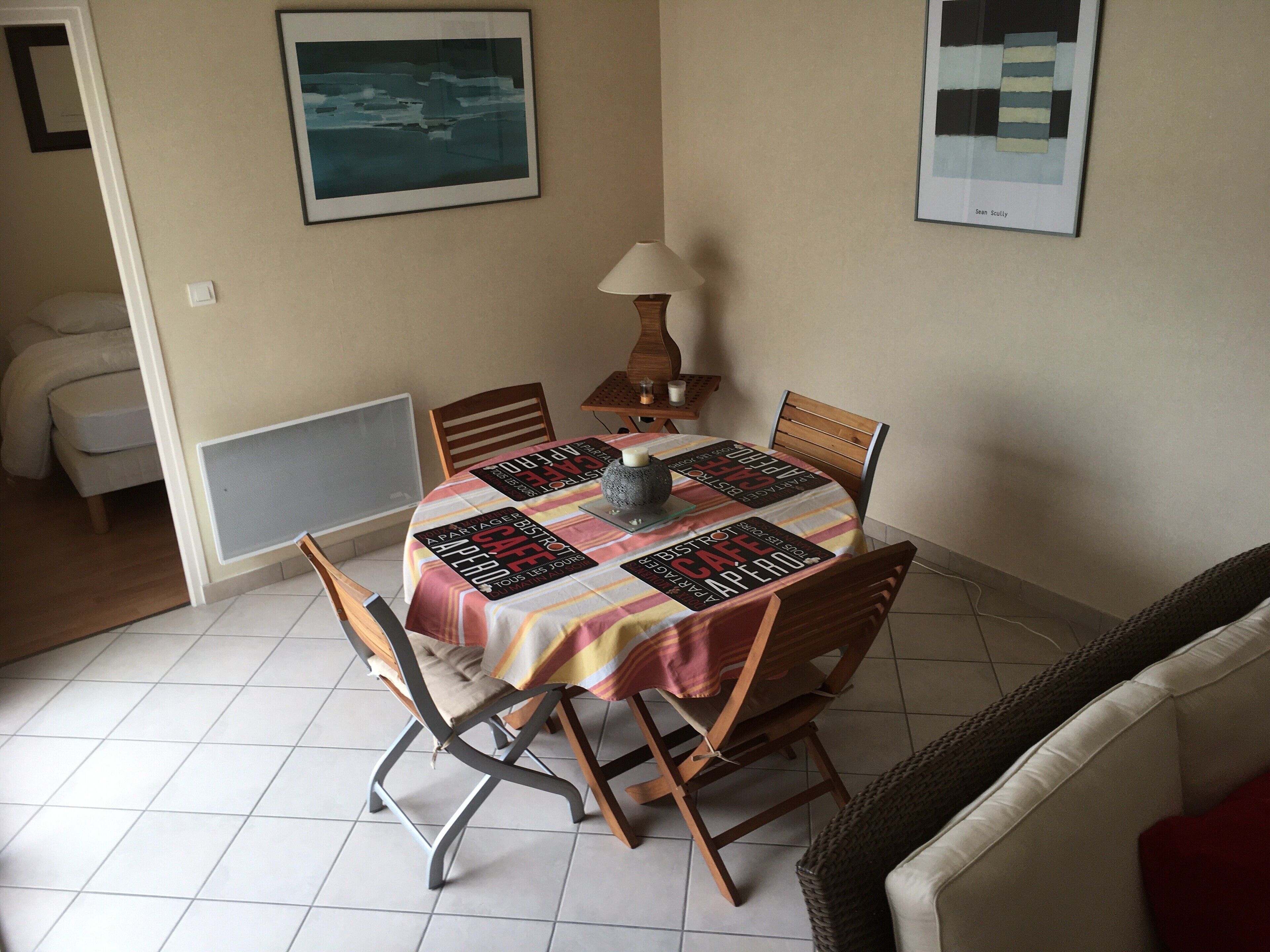 A dining area with a table covered by a patterned tablecloth, surrounded by wooden chairs.