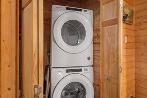 Two stacked white AMANA washing machines in a wooden cabin with a sign that reads "Cabin". - Secluded Cabin, HotTub, Jet Tub, Woods, Near Big Cedar & Shows-Firepit -Car Charger (Ridgedale)