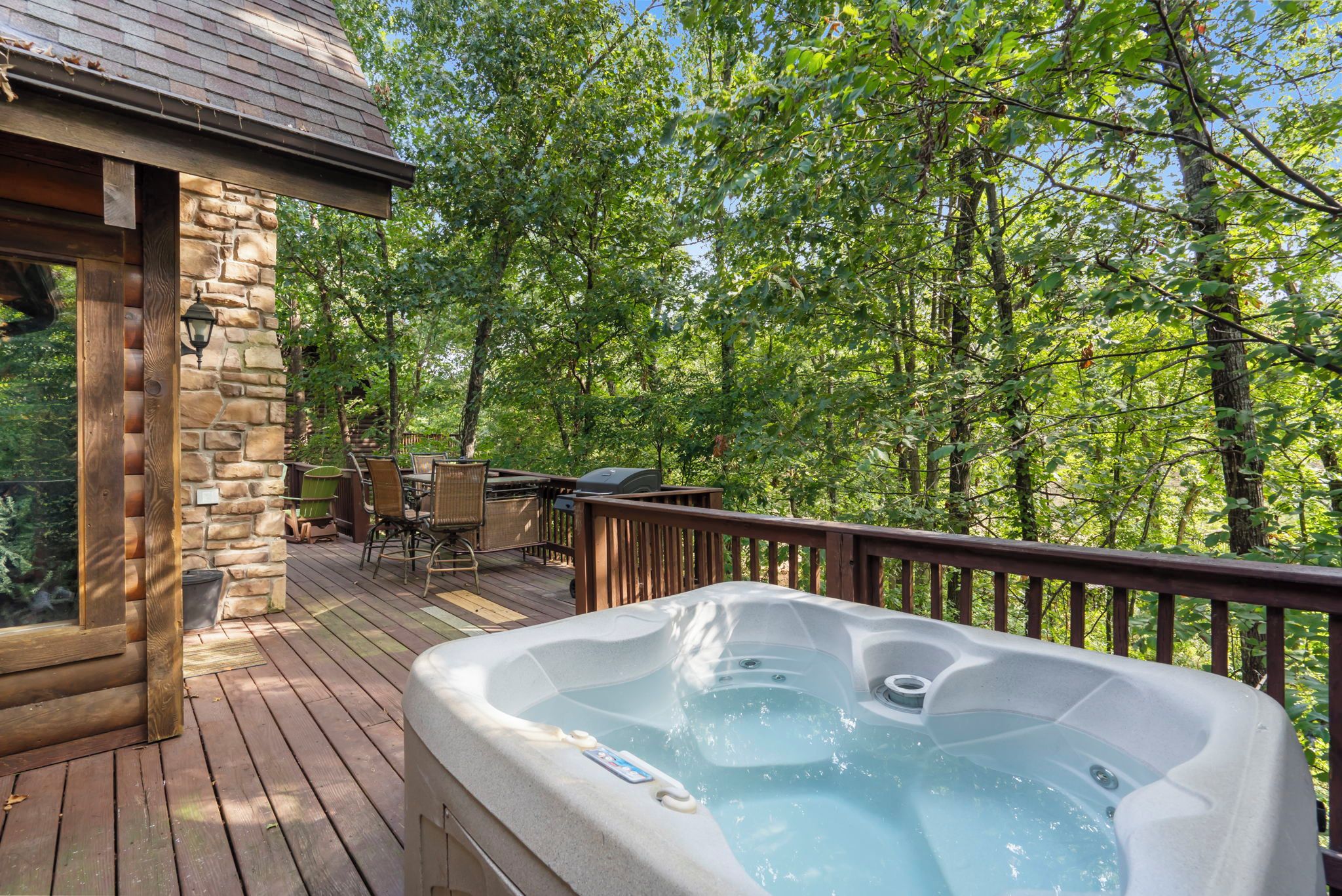 A hot tub on a wooden deck surrounded by trees.