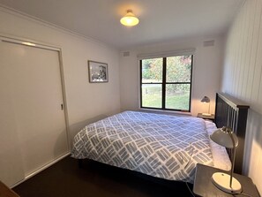 Une chambre à coucher avec un lit, une fenêtre, une lampe de chevet et un tableau au mur.