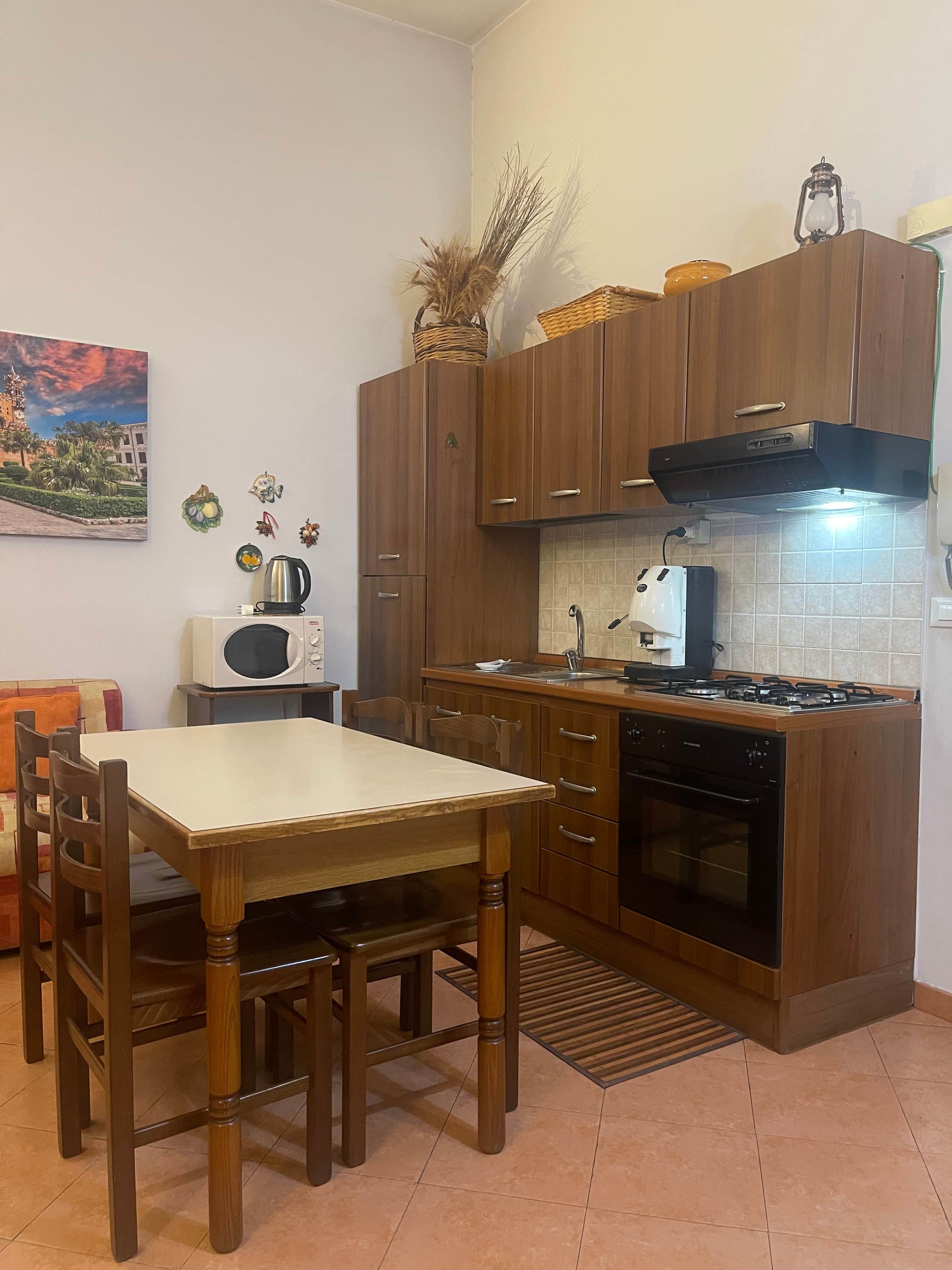 A compact kitchen with wooden cabinets, a gas stove, a microwave, and a sink.