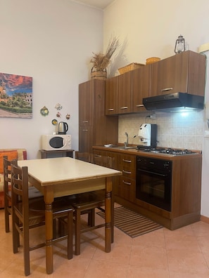 A compact kitchen with wooden cabinets, a gas stove, a microwave, and a sink.