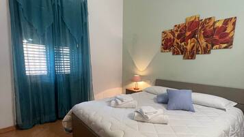 A hotel room with a bed, a nightstand, a lamp, and a painting on the wall.